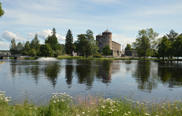 Fototapeta na wymiar Idyllic view across the lake towards Olavinlinna Castle in the small town of Savonlinna, Finland. The castle was founded in 1475.