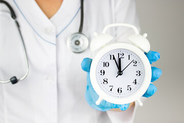 The concept of medicine and health insurance. Doctor hand with alarm clock. Health care and...