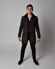 Full length portrait of a brunette man wearing black leather coat.  Standing pose isolated against...