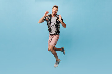Fototapeta na wymiar Scared bearded man in black summer shirt, plaid t-shirt and modern shorts looking into camera, screaming and looking into camera..