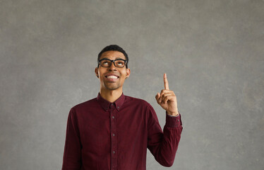 African american young man looking and pointing finger at empty space on gray background. Happy smiling young casual man with glasses has an idea to solve. Concept of ideas and decision making. Banner