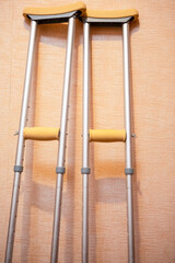 Medical and Health Concept. Pair of Crutches for Disabled People Placed Against Wall Indoors.