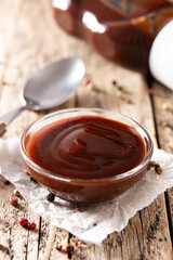 Barbecue sauce in a bowl on rustic wooden table - obrazy, fototapety, plakaty