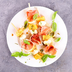 melon salad on stick with mozzarella and prosciutto ham