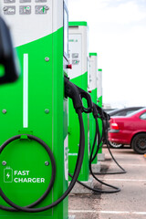 Alternative Energy Concept. Electric Car or EV Car Charging At Station With Power Cables  Hanged on Stations.