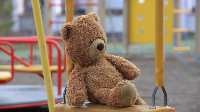 Forgotten Teddy Bear on a Childrens Swing in an Empty Playground. Concept Childhood, Psychology, Family Relations, Foster Child, Kindergarten, Orphanage