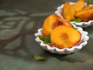 Caramelized peaches with honey, with mint leaves on a concrete background with shadows. Summer dessert.