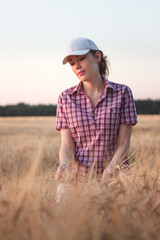 Beautiful girl in a cap on a rye field. Young girl in wheat field at sunset background