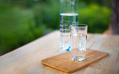 A glass and a bottle of mineral water on the table in the garden.