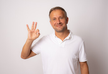 Portrait of a cheerful young man showing okay gesture isolated on the white background