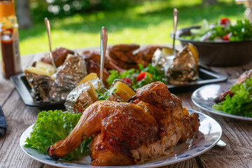 Barbecue meal with grilled chicken, baked potatoes and salad in the garden