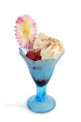 Cream flavored ice cream with raspberries in blue glass cup with colorful paper flower decoration isolated on white, copy space