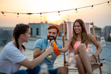 Happy friends toasting with drinks at a rooftop party