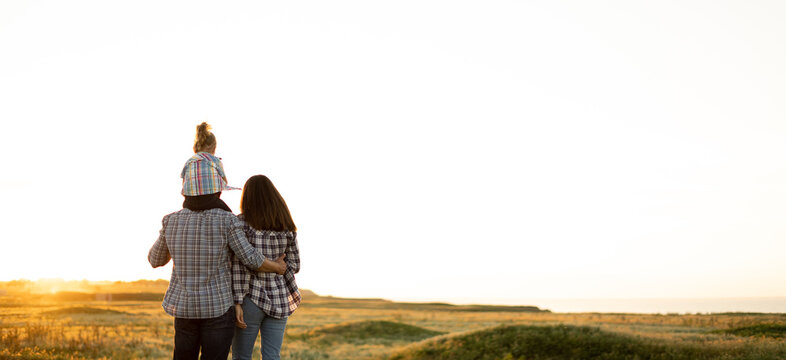 family tourists mother father and daughter child at sunset. Back view and silhouettes in summer evening. Happy family relationship concept. Parenting and childhood. Travel as a way of life.