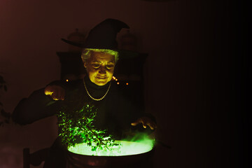 old witch making potions in a copper pot. older woman performing witchcraft.