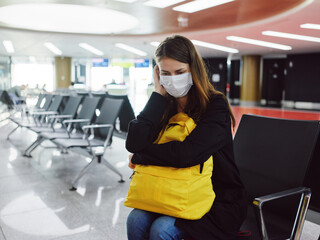 tired woman in medical mask with luggage airport waiting flight delay