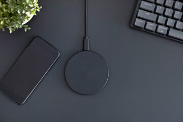 Flatlay of office desk. Smartphone, wireless charger and computer keyboard.