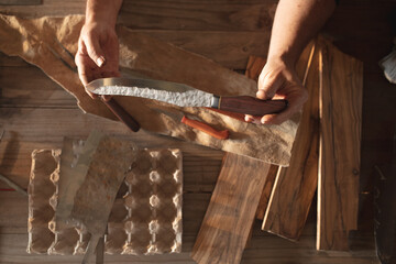 Hands of caucasian male knife maker in workshop, holding handmade knife