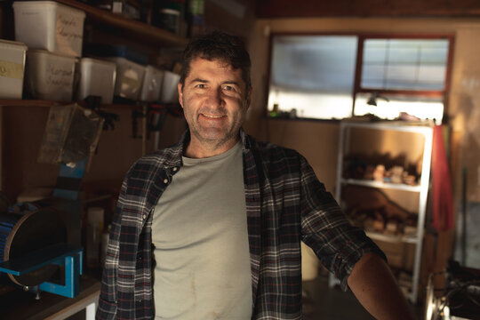 Smiling caucasian male knife maker in workshop looking at camera