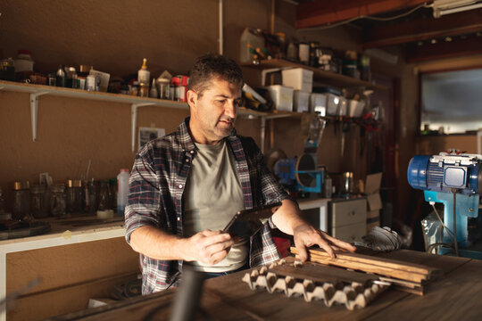 Caucasian male knife maker preparing mold, using tablet in workshop