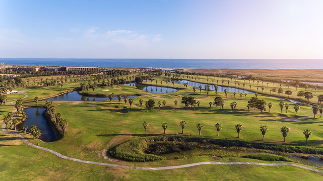 Green golf courses by the sea. Salgados beach. Portugal, Albufeira. Aerial view and high trees, sunny day 