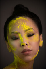 Portrait of asian woman with yellow powder paint