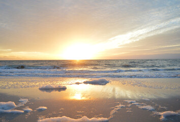 Beautiful landscape of sea foam on the shore of Naples beach during sunset hour