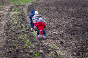 small children ride each other on a bicycle across the field
