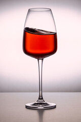 A close-up of a clean glass filled with red wine on the white background. Wavy surface, no splashes. Restaurant glassware, serve, romance, passion, love.