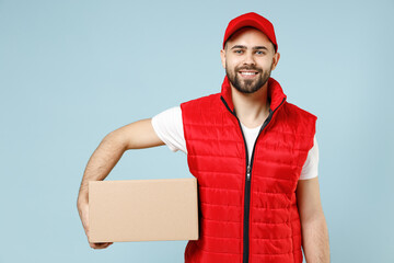 Professional delivery guy employee man in red cap white T-shirt vest uniform workwear work as dealer courier hold blank cardboard box isolated on pastel blue color background studio. Service concept. - obrazy, fototapety, plakaty