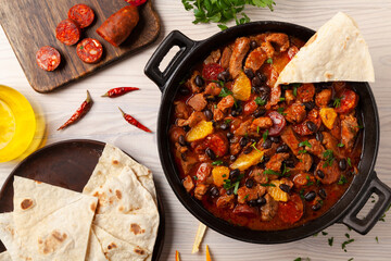 Pork stew with chorizo and black beans. Served with orange and seasoned with hot chili peppers. Perfect with tortillas.