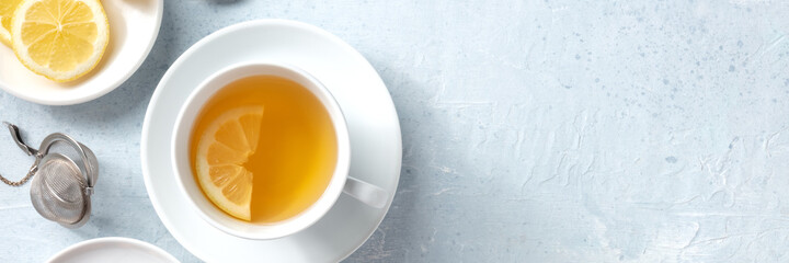 Lemon tea panorama with copy space. A cup of tea with a slice of fresh lemon, shot from the top on a slate background