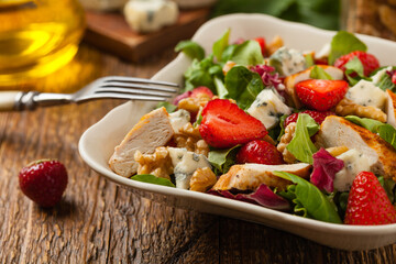 Delicious salad with fried chicken, blue cheese, strawberries and walnuts. Front view.