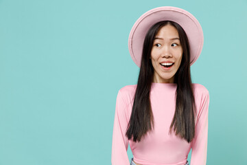 Surprised fascinating smiling stunning fun young brunette asian woman 20s wears pink clothes hat look aside isolated on pastel blue color background studio portrait. People emotions lifestyle concept