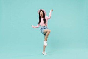 Fototapeta na wymiar Full size body length fun laughing happy jubilant young brunette asian woman 20s wears pink clothes standing on one leg wink spreading hands isolated on pastel blue color background studio portrait