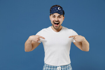 Naklejka premium Young impressed surprised leader man 20s wear pajamas jam sleep mask white t-shirt rest relax at home point index finger on himself isolated on dark blue background Good mood night bedtime concept