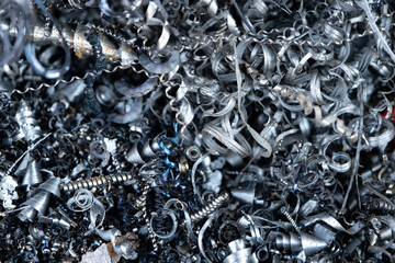 Steel scrap materials recycling. Aluminum, iron chip waste after machining metal parts on a cnc lathe. Closeup abstract twisted spiral steel shavings. Small roughness sharpness, blurred focus