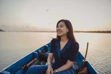 Fototapeta premium A girl is smiling on the boat sailing in the sea during sunrise