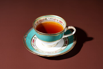 Hot tea in an antique cup and saucer on a brown background