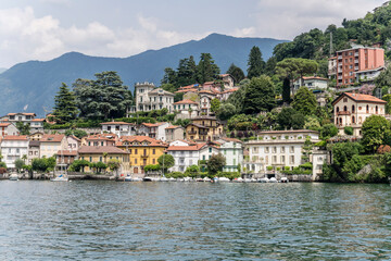 Fototapeta na wymiar old houses on lakeside at green lake shore, Como, Italy