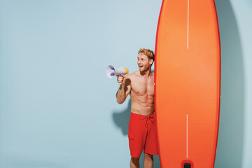 Handsome young sexy sporty blond man in red shorts swimsuit relax stand near orange sup board...