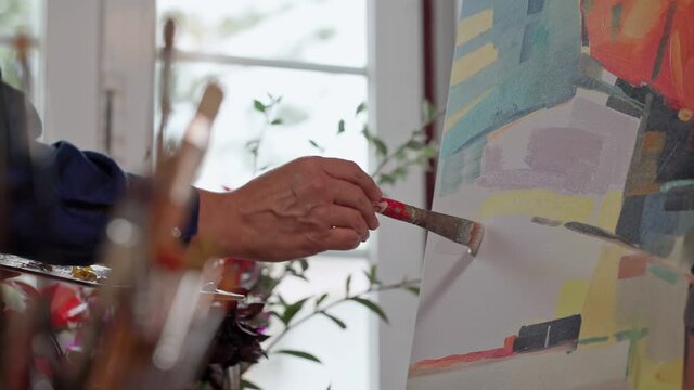 Woman artist applying paint with brush strokes on canvas, brush close-up. Abstract painting. Slow motion