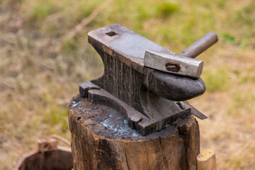 Hammer and blacksmith anvil at outdoor forge, workshop - selective focus, close up. Handmade, craftsmanship and blacksmithing concept