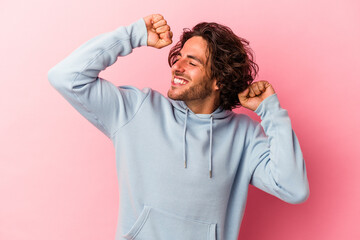 Young caucasian man isolated on pink bakcground celebrating a special day, jumps and raise arms with energy.