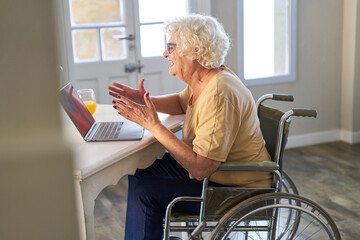 Seniorin im Rollstuhl am Computer macht einen Video Call