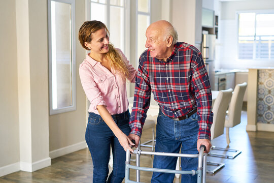Junge Frau hilft Senior Vater beim gehen mit dem Rollator