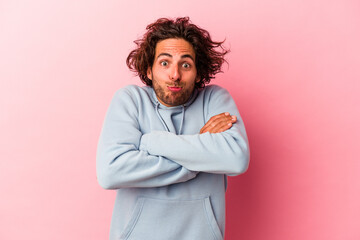Young caucasian man isolated on pink bakcground shrugs shoulders and open eyes confused.