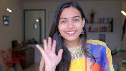 Attractive young Indian female in a traditional sari saying hi at home © Media Nation/Wirestock