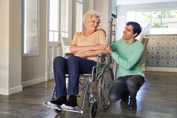 Mann und glückliche Seniorin im Rollstuhl nach Schlaganfall