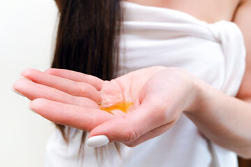 A young woman pours oil into her palm.